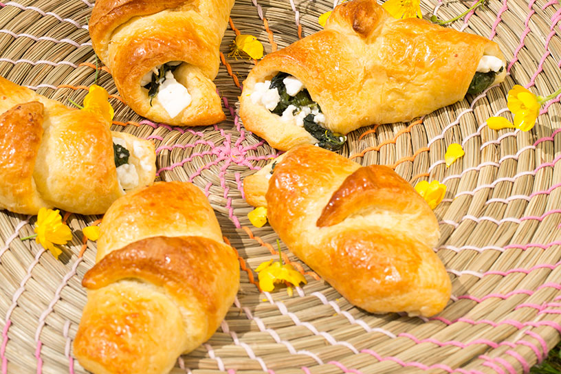 Zomerse croissants gevuld met spinazie en feta gedecoreerd met gele bloemblaadjes